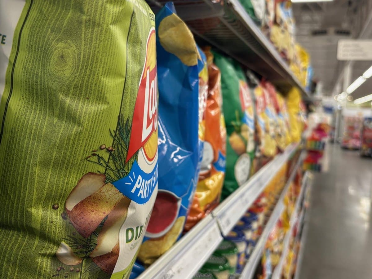 A convenience store snack aisle filled with chips and packaged snacks